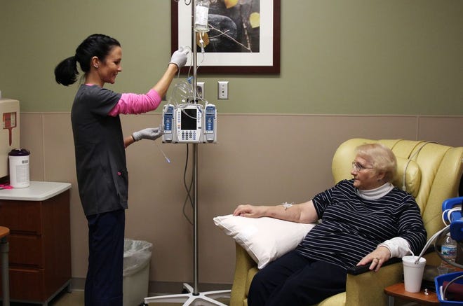 In this Dec. 22, 2015 photo, nurse Nicole Krahn, left, gets rheumatoid arthritis medication ready for semi-retired nurse Lynn Bartos at Froedtert & the Medical College of Wisconsin in Wauwatosa, Wis. The two have switched roles from more than 25 years ago, when Bartos cared for Krahn as a toddler. (AP Photo/Carrie Antlfinger)