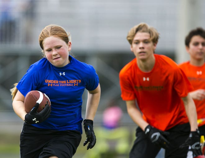 Emma Wyman, 11, runs the ball for her flag football team Saturday at Trinity Catholic in the new league sponsored by UnderArmour. The 19-team league with more than 160 players will compete the remainder of the season on Friday nights.