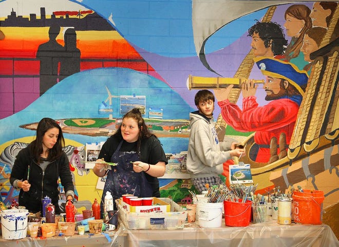 Hull High School art teacher Amanda Davis and students Carolynn Buckley, 17 and Brian Santry, 18, work on the mural in the school's cafeteria. Cambridge artist David Fichter provided guidance as students created the mural, which shows a variety of Hull scenes. The photo was taken on Wednesday, Jan. 13, 2016.