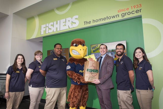 Student Leadership and Activities Board members Madison Hoenes, April Arbogast, Neal Dingies, Ashley Spellman and Natalie Lucas show off Flash's Food Pantry at Kent State University Stark Campus with Fishers Foods Director of Store Operations Alex Fisher, third from right, holding grocery bag.
