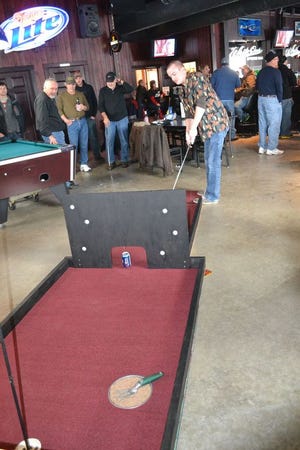 A contestant at the 2014 Glacial Golf fundraiser for Canton Main Street tries to sink a putt on the course at one of the participating bars. The annual fundraiser kicks off at 11 a.m. today at Moore’s Pub.