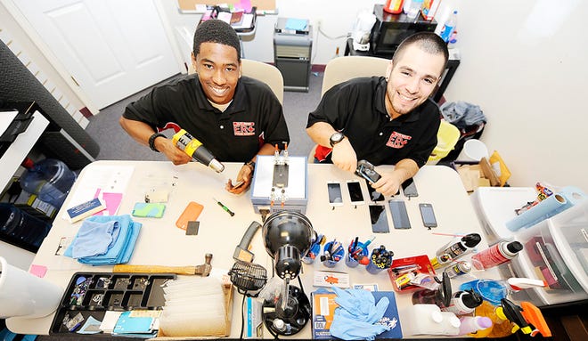 Markqone Russell and Isaac Gradeless repair cellphone screens at their shop, Elite Repair Phone Services in downtown Adrian.