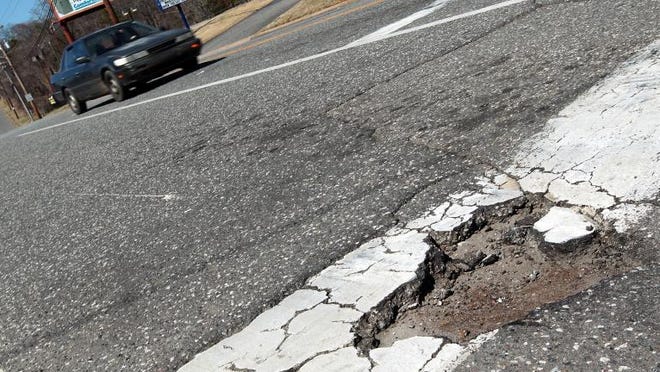 (Photo Mike Hensdill/The Gaston Gazette ) A car passes near a pothole at the intersection of Reamount Road and Aberdeen Blvd. Saturday afternoon, March 7, 2015.