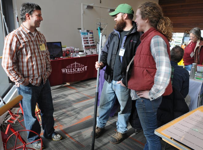 Peter Gile, left, of Two Bad Cats, talks with Brian Cunningham and Alice Colman of Stony Hill Farm in Wilbraham about Mr. Gile 's wire weeder during the Northeast Organic Farming Association 29th annual Winter Conference at Worcester State University on Saturday.  T&G Staff/Christine Hochkeppel