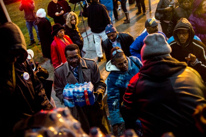 Flint residents line up for free bottled water as activists protest outside of City Hall to protest Michigan Gov. Rick Snyder's handling of the water crisis Friday, Jan. 8, 2016 in Flint. Mich. (Jake May/The Flint Journal-MLive.com via AP)