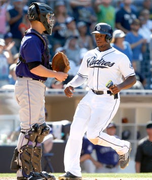 San Diego Padresí Justin Upton, right, scores on a double by Jedd Gyorko with Colorado Rockies catcher Dustin Garneau, left, looking on during the fourth inning of a baseball game in San Diego, Calif., Monday, Sept. 7, 2015.