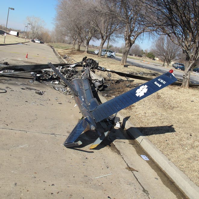 Below: This photo from a National Transportation Safety Board records shows a close-up rear view of the helicopter wreckage in the street next to a curb.