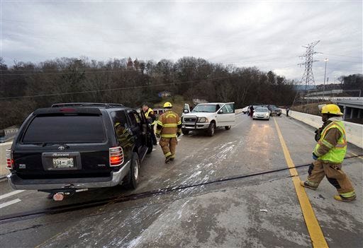 Emergency personnel work the scene were a motorist lost control and jumped the guardrail after hitting a patch of ice on US 27 North in Chattanooga, Tenn., on Wednesday , Jan. 20, 2016. A winter storm with freezing rain left slick roads for morning commuters. (Dan Henry/Chattanooga Times Free Press via AP)
