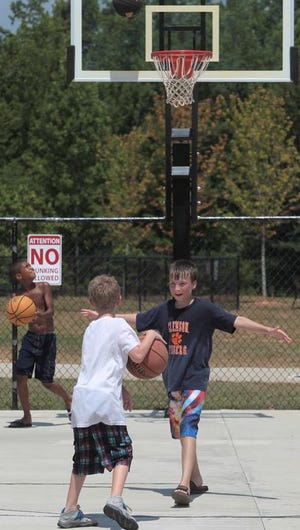 (Photo Mike Hensdill/The Gaston Gazette) There is a plan to raise $400K to build a new town gym at Harper Park in Stanley. Here, (L-R) Davashia Good3 (10),Tyler Murray (9) and Dustin Black (13) play on the basketball court at Harper Park on Blacksnake Road in Stanley Wednesday afternoon, June 24, 2015.