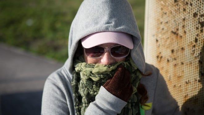 Lauren Huttel, of West Palm Beach, pulls her scarf over her face as she waits for the bus on South Dixie Highway on Friday, January 17, 2014 in West Palm Beach. (Madeline Gray/The Palm Beach Post)