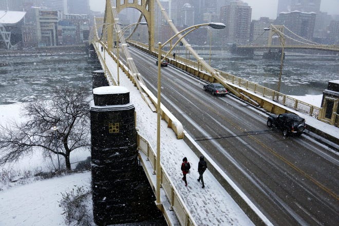 People walk across the Rachel Carson bridge across the Allegheny River toward downtown Pittsburgh as snow falls Wednesday evening. Southeast Pennsylvania could be in for heavy snow this weekend.