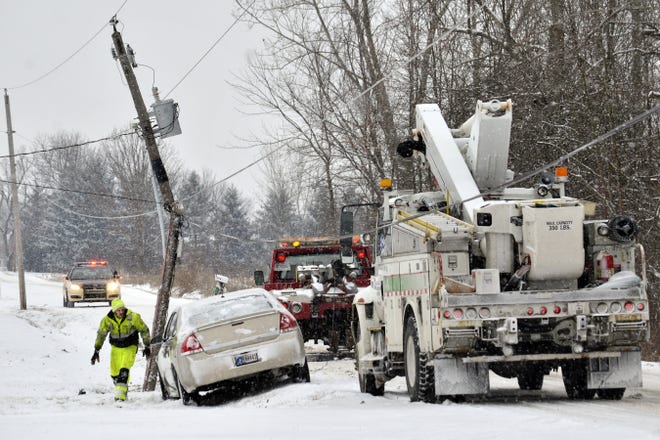 An Indiana Michigan Power truck stands by as a wrecker operator prepares to tow a car that struck and broke a utility pole in Grant County, Ind., east of Marion, on Wednesday, Jan. 20, 2016. No one was injured in the accident. (Jeff Morehead/The Chronicle-Tribune via AP)
