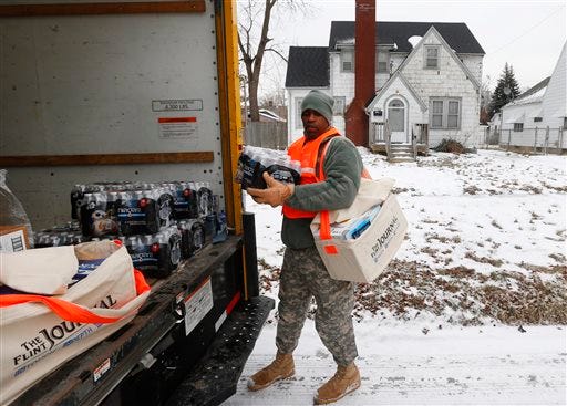 Michigan National Guard Specialist Lonnie Walker unloads bottled water and filters to distribute to residents, Thursday, Jan. 21, 2016 in Flint, Mich. The National Guard, state employees, local authorities and volunteers have been distributing lead tests, filters and bottled water during the city's drinking water crisis