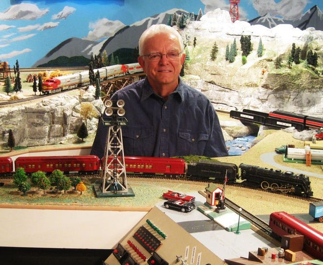 Rod Price sits in the midst of the rail scene he has created in the basement of his Astoria home. His railroad features 230 linear feet of track on two levels.