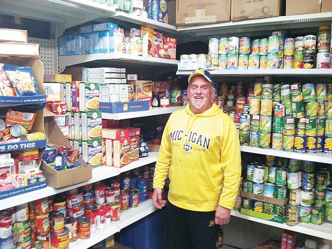 Daily Bread of Lenawee food pantry services coordinator Ken Freshcorn stands in front of the pantry’s freshly filled shelves from a donation given in memory of Ed Monday and his Main Street Market.