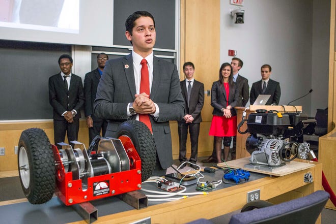 In this December 2015 photo provided by Harvard University, junior Cesar Maeda explains a robotic snow blower to a group of officials at Harvard in Cambridge, Mass. (Photo by Eliza Grinnell/Harvard University John A. Paulson School of Engineering and Applied Sciences via AP)