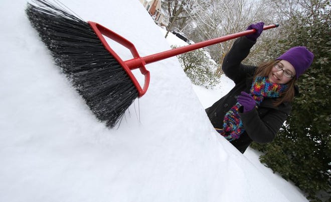 (Photo Mike Hensdill/The Gaston Gazette ) Snow and ice continued to cause minor problems Saturday, Jan. 23, 2016 after a winter storm swept through the area. Here, Jessica Holbrook uses a broom to push snow off her car on Home Trail in Gastonia.