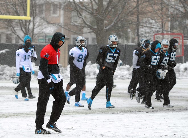 Carolina Panthers quarterback Cam Newton, left, walks across a practice field covered in snow and ice, Friday, Jan. 22, 2016, in Charlotte, N.C. The Panthers host the Arizona Cardinals in the NFC championship NFL football game on Sunday.