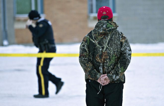 A man holds a rosary as police investigate the scene of a shooting at the community school in La Loche, Saskatchewan, on Saturday, Jan. 23, 2016. The shooting took place on Friday. Saturday, Jan. 23, 2016. (Jason Franson/The Canadian Press via AP)