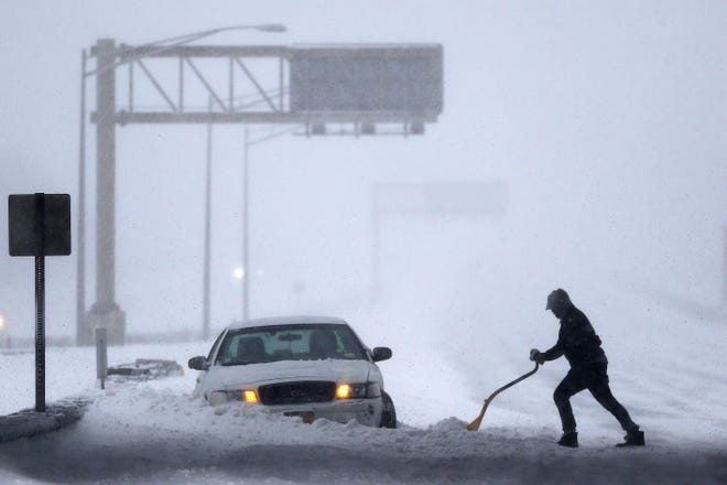 A motorist shovels snow to free up a vehicle on the New Jersey Turnpike during a snowstorm, Saturday, Jan. 23, 2016, in Port Reading, N.J. Towns across the state are hunkering down during a major snowstorm that hit overnight. (AP Photo/Julio Cortez)
