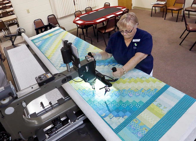 Miriam Harcek works on a "Trip Around the World" quilt on the Lake Region Village Quilt Club long armed quilting machine at the village clubhouse near Haines City. PIERRE DUCHARME/THE LEDGER