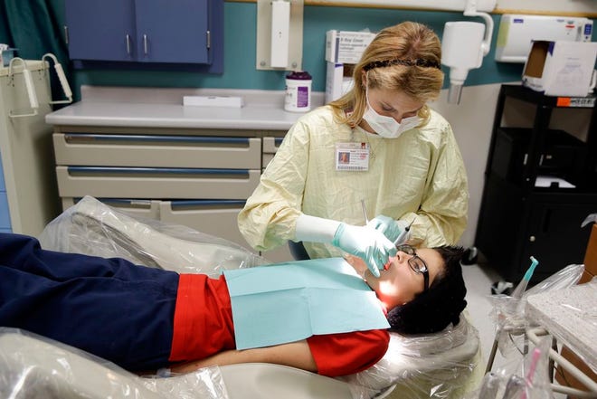 In this Friday, Jan. 22, 2016 photo, dental resident Madison Myers Galloway checks the teeth of Justin Perez, 11, during an office visit at Riley Hospital for Children's Department of Pediatric Dentistry in Indianapolis. A federal report says three out of four children did not receive all required dental services, such as regular checkups and fluoride treatments, in Medicaid programs in four states. One in four kids failed to see a dentist at all. (AP Photo/Michael Conroy)