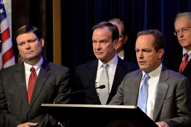 Michigan Attorney General Bill Schuette, center, announces Todd Flood, right, a former assistant prosecutor for Wayne County, and retired Detroit FBI chief Andrew Arena, left, will spearhead an investigation and serve as special counsel in the investigation into Flint's lead-tainted water during a news conference Monday, Jan. 25, 2106 in Lansing, Mich. (Dave Wasinger/Lansing State Journal via AP) MANDATORY CREDIT