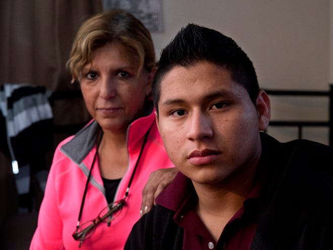 Marvin Velasco, 15, right, poses for a photo with his new sponsor, Ingrid Ainspac, at their home in Los Angeles on Monday, Jan. 11, 2016. After escaping from a previous sponsor who was abusive, he sought sanctuary in a nearby church, where he met a parishioner who took him in and became his legal guardian. He now lives with a Guatemalan immigrant family, which is raising him as a son. (AP Photo/Mark J. Terrill)