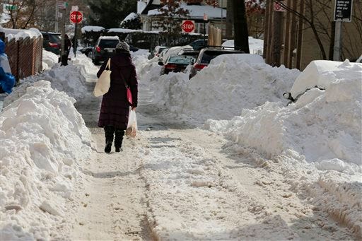 With sidewalks covered in snow, a woman walks down a Queens street on Monday.