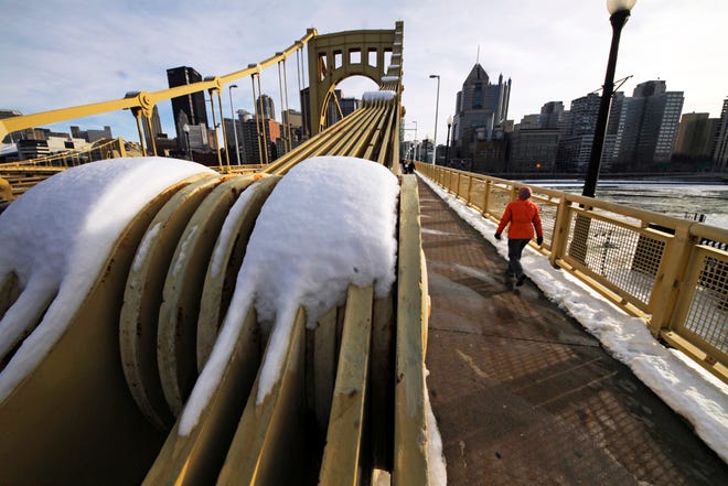 A woman walks across the Roberto Clemente bridge over the Allegheny River in downtown Pittsburgh, Monday, Jan. 25, 2016. (AP Photo/Gene J. Puskar)