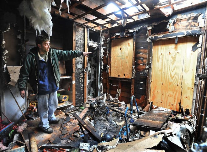 Standing in his fire-ravaged home, Craig Warner talks about the side entry where the fire started. He's standing in what had been his 3 year old son's playroom. Herald News Photo | Jack Foley