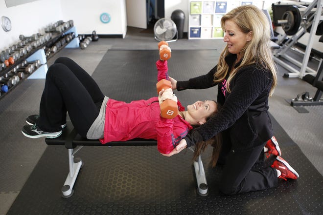 Heidi Jones, owner of Heidi's Fitness Studio in Middletown, blocks Bre Power Eaton from overextending her elbows during a chest press, encouraging her all the while to protect her back by engaging her abs.