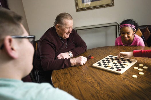 Joe Frakes of Creve Coeur plays a game of checkers with his adopted grandchildren, including Anthony, 14, left, Vanessa, 8, and Jordan, 12, making a move on the checker board.