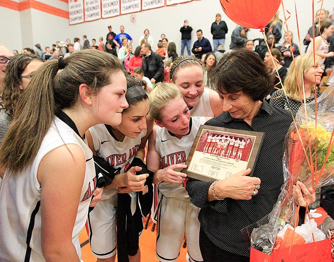 Oliver Ames players look at a photo from the 1978-79 coaching season of coach Elaine Clement-Holbrook after the coach's record-setting 634th win Tuesday, Jan.26, 2016.
