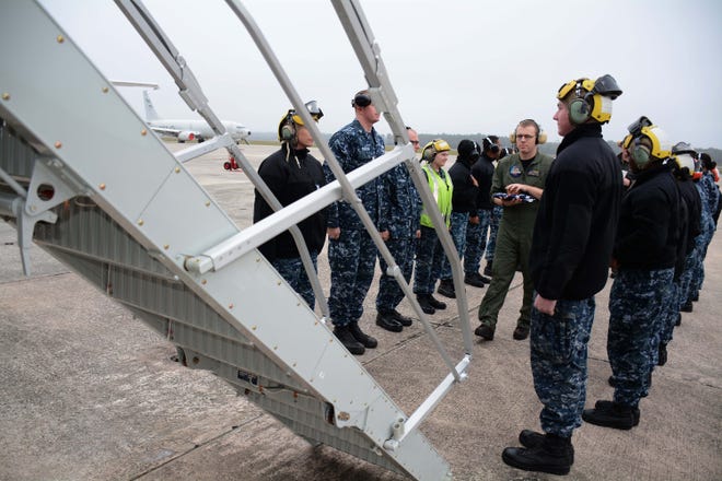 Lt. Joseph Johannes (middle), a naval flight officer with Patrol Squadron (VP) 45 carries the ashes of James Lincoln "Linc" Sparks Sr., a former member of VP-45, aboard one of the squadron's P-8A Poseidons during a burial-at-sea ceremony Jan. 7 at Cecil Airport.