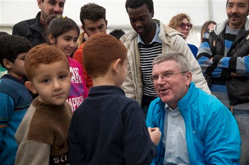 IOC President Thomas Bach, chats with children during his visit at a refugee camp in Athens on Thursday, Jan, 28, 2016. Bach says the torch relay for this year's Olympics in Rio de Janeiro will include a stop at a refugee camp in Athens. He also promised to build sporting facilities on the island of Lesbos that has been hard hit by the migrant crisis.(AP Photo/Petros Giannakouris)