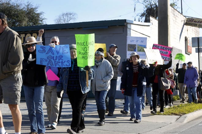 Local citizens protest plans to expand hunting, logging and grazing in state parks while marching Saturday from Gainesville's First Magnitude Brewery.