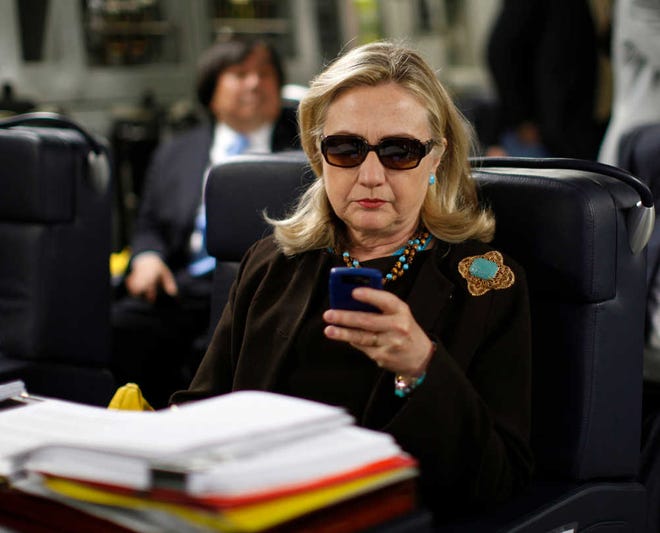 FILE - In this Oct. 18, 2011, file photo, then-Secretary of State Hillary Rodham Clinton checks her Blackberry from a desk inside a C-17 military plane upon her departure from Malta, in the Mediterranean Sea, bound for Tripoli, Libya. The Obama administration is confirming, Friday, Jan. 29, 2016, for the first time that Hillary Clinton's unsecured home server contained some closely guarded secrets, including material requiring one of the highest levels of classification. (Kevin Lamarque/Pool Photo via AP, File)
