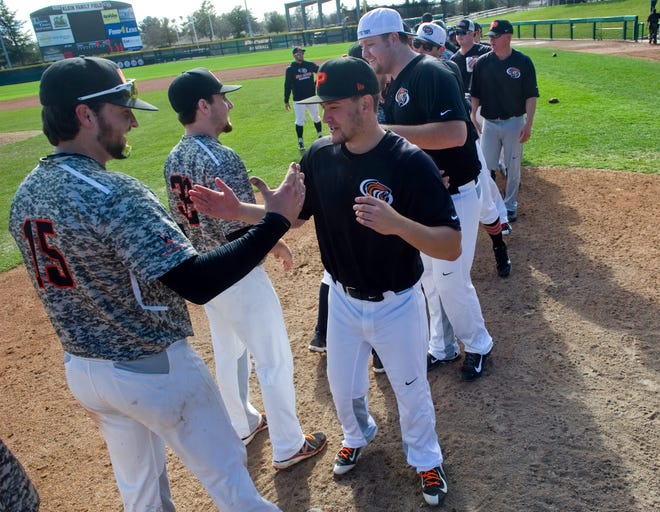 Pacific baseball players (in camouflage jerseys) congratulate Pacific alumni players after an alumni game on Saturday at Klein Family Field. CLIFFORD OTO/THE RECORD