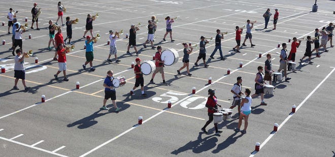 Students march with their water bottles nearby during band practice at Coronado High School in Lubbock.