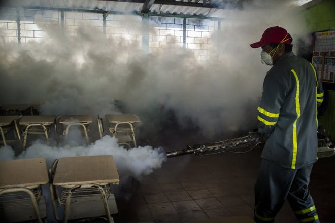 A city worker fumigates a classroom in a mosquito eradication effort in Santa Tecla, El Salvador, last week.