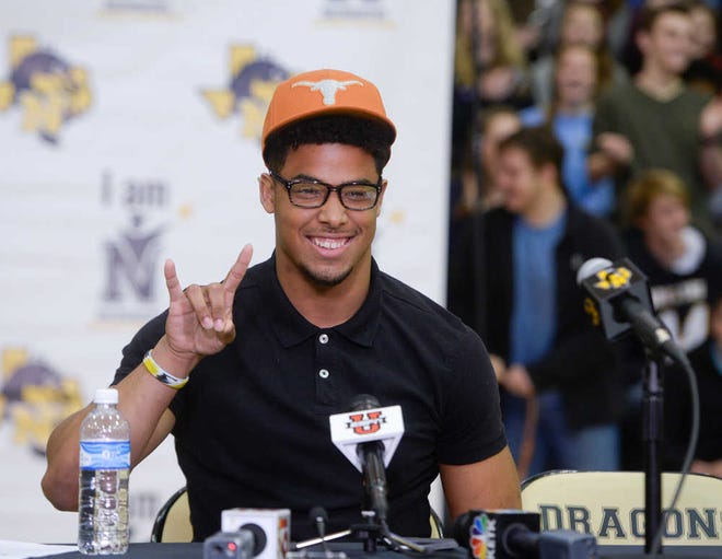 Nacogdoches High School football player Brandon Jones gestures with a "hook 'em horns" sign as he announces that he will be attending the University of Texas to play NCAA college football, Wednesday, Feb. 3, 2016, during a national signing day event in Nacogdoches, Texas, (Victor Texcucano/The Daily Sentinel via AP) MANDATORY CREDIT