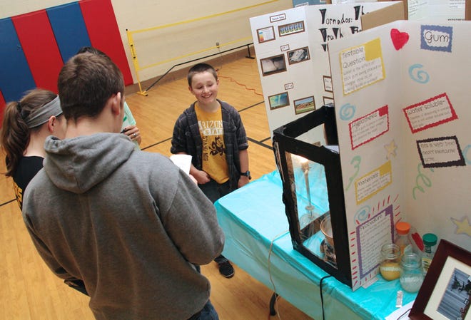 Brysen Schaffer a student at Reynolds Elementary School, discusses his science fair project, "Tornadoes the Truth Behind the Magic," with Michael Lane and Sam Pfieffer. ANDY BARRAND PHOTO