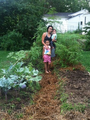 A family shows off their bountiful garden, built through the Columbia Center for Urban Agriculture’s Opportunity Garden program. CCUA works with qualifying participants to build and plant gardens, then continues to mentor them on such topics as garden maintenance, food preservation methods and cooking over the course of three years.