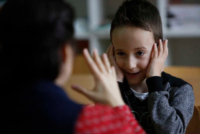 In this photo taken Thursday, Feb. 4, 2016, Bosnian boy Zejd Coralic, right, learns sign language from teacher Anisa Setkic-Sendic in a class at an elementary school in Sarajevo, Bosnia. In 2003, Bosnia adopted laws that allow children with disabilities to be fully integrated into society, including schools. Children with special needs are supposed to have professional assistants who sit with them in class, translating or otherwise helping them participate. But in practice, impoverished Bosnia barely has enough money to keep normal schools functioning and children with disabilities are left to the care and imagination of their parents and the good will of school staff. (AP Photo/Amel Emric)