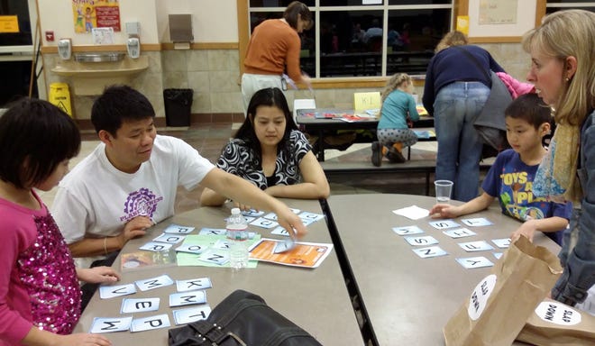 At family game night in Somersworth, Tien, Chau, Hong, and Phuc Doan enjoy a fast-paced word game run by Kathy Hilliard, Title 1 home to school coordinator. Photo by Judi Currie/Fosters.com