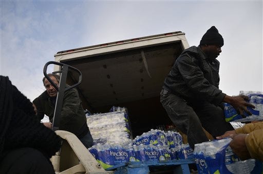 From left, Sunridge Apartments employee Rex Robinson and Raymond Lavigne, of Dixmoor, Illinois, unload a truck that carried cases of bottled water from Thornton Township on Saturday, Feb. 6, 2016 at Sunridge Apartments in Flint Township, Mich. Thornton Township in Illinois drove with 20 volunteers to donate bottled water to Flint Township.