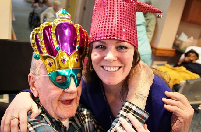 Marina Bay's activities director, Sarah Moran, shares a hug with the Mardi Gras king, Harry Gill, on Tuesday, Feb. 9, 2016. Residents celebrated Fat Tuesday by putting on masks and beads, having cake and holding a parade.