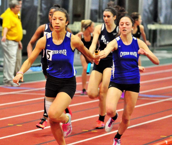 Oyster River's Maegan Doody, right, hands off to Dominque Twombly for the final leg of the team's record-setting 4x200-meter relay on Sunday in Hanover. Mike Whaley/Fosters.com