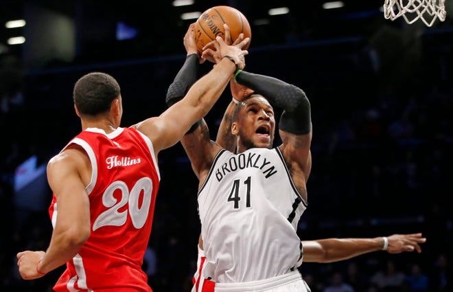 Grizzlies center Ryan Hollins (20) gets a hand on the ball as Nets forward Thomas Robinson attempts a shot during the second half of Wednesday night's game in Brooklyn. The Associated Press